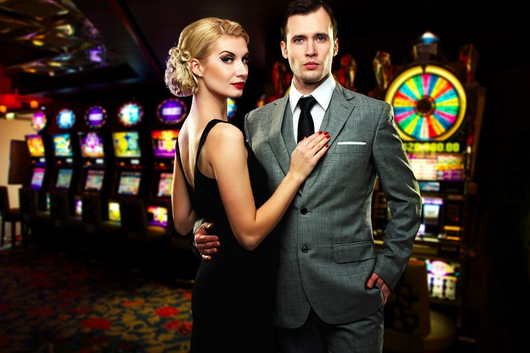 Beautiful couple in a casino at slot machines